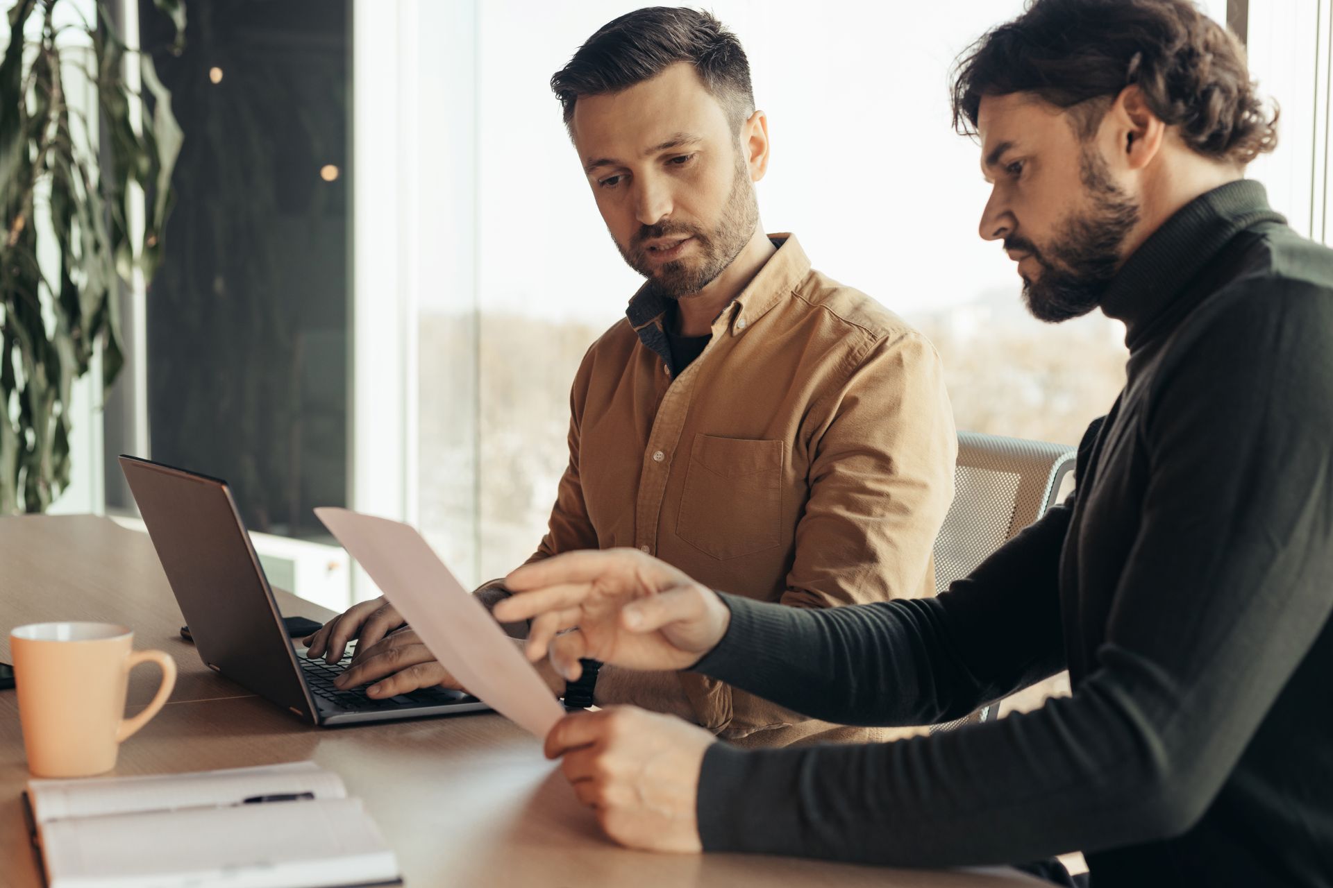 serious-company-workers-looking-through-document-collaborating-using-laptop-modern-office-copy